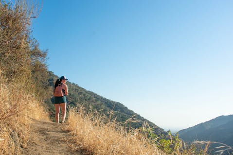 Woman hiking on the Keiser Trail overlooking a big view of the San Gabriel Mountains below in Big Dalton Canyon Wilderness in Los Angeles County