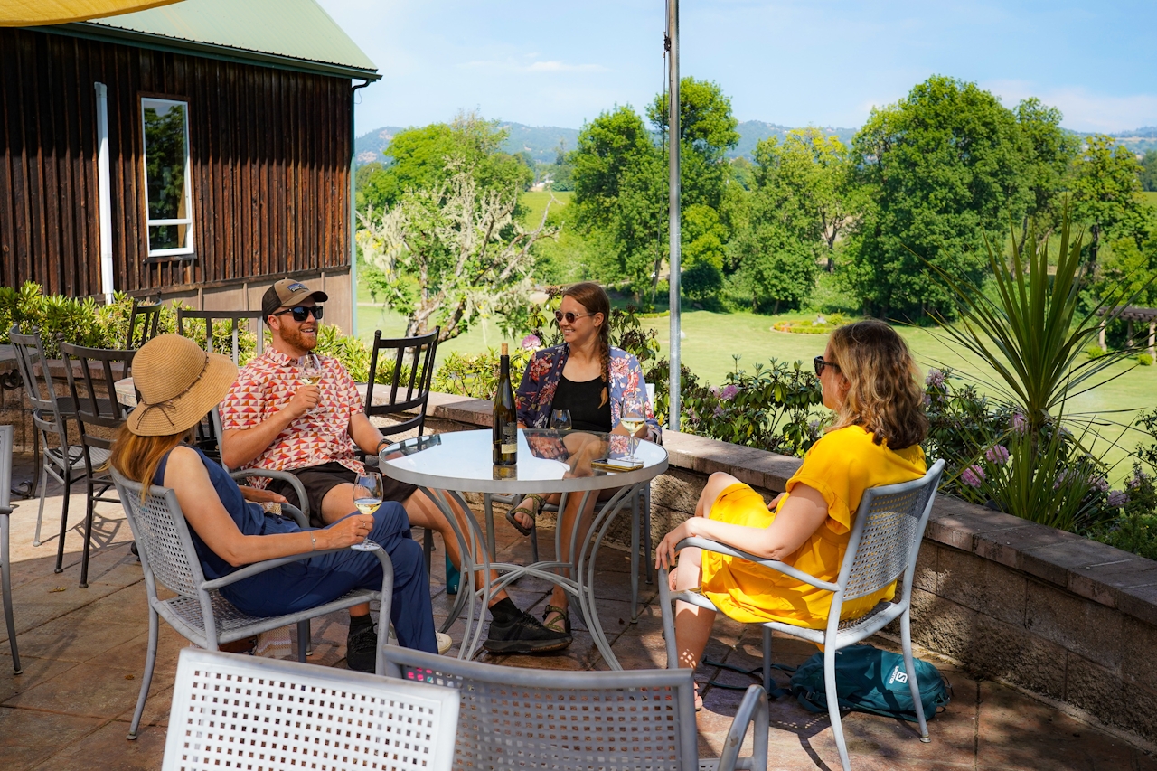 A group of friends sitting around a table overlooking the vineyard at Melrose Vineyard near Roseburg Southern Oregon 