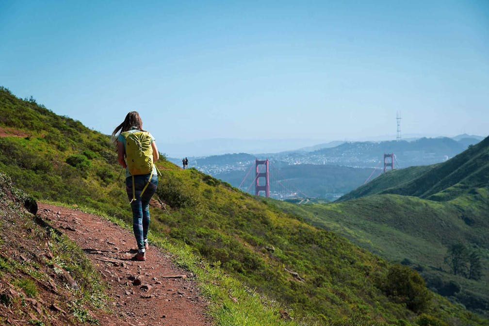Hiker on the SCA trail in Marin Headlands with view of the Golden Gate Bridge 