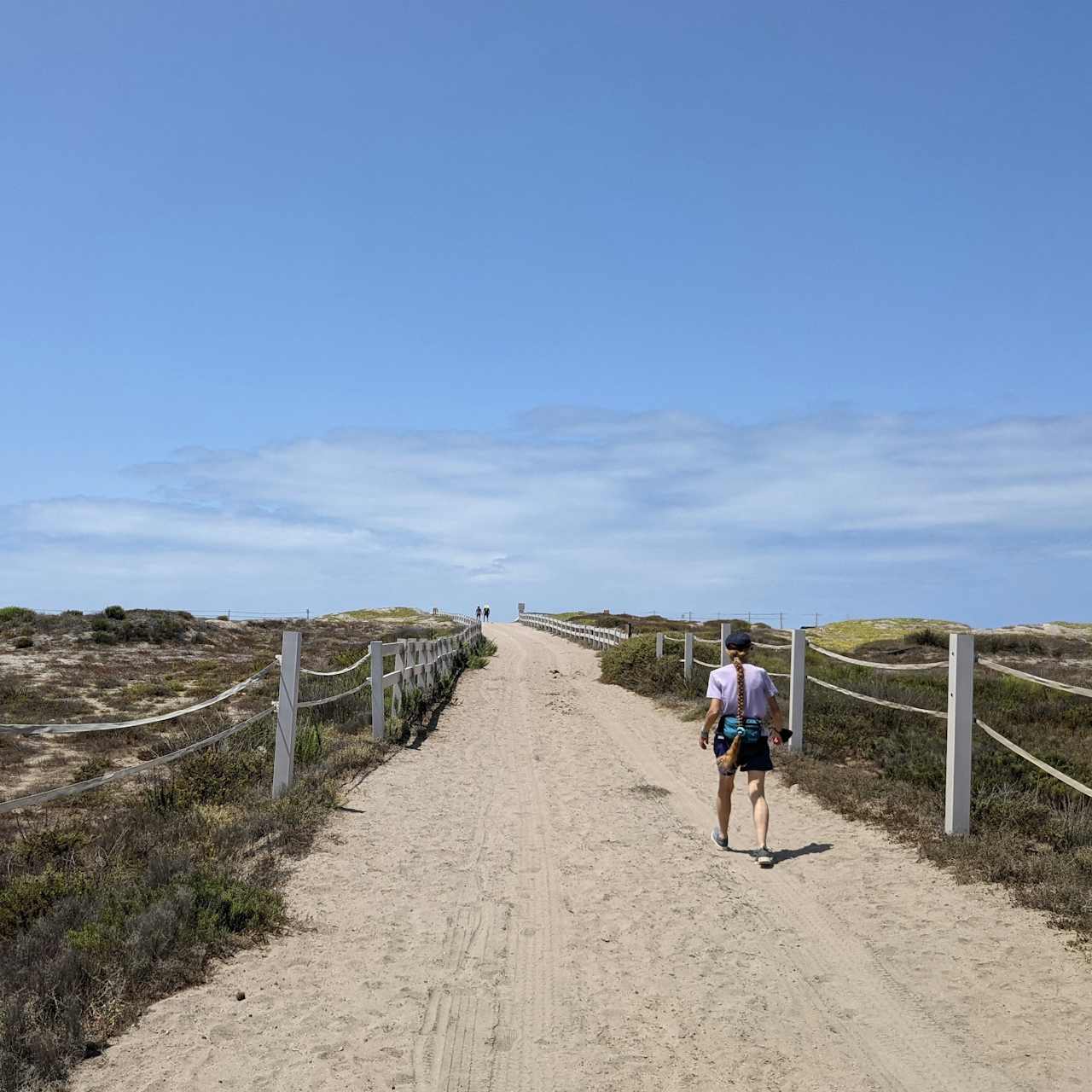 Woman hiking a wide and sandy trail at Border Field State Park in San Diego County  