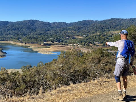 Hiker pointing towards the Lexington Reservoir at the high point of St. Joseph's Hill in Los Gatos