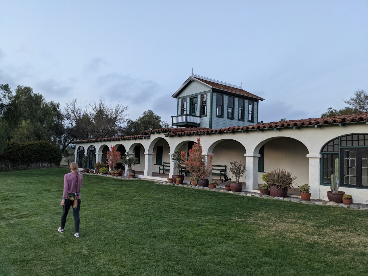 Woman walking outside the Rancho Guajome Adobe in Guajome County Park 