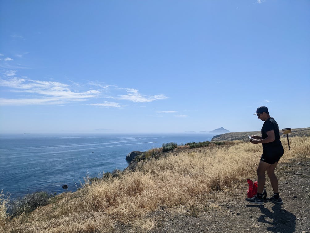 Person looking at their phone while overlooking the sea scenery at Santa Cruz Island National Park 