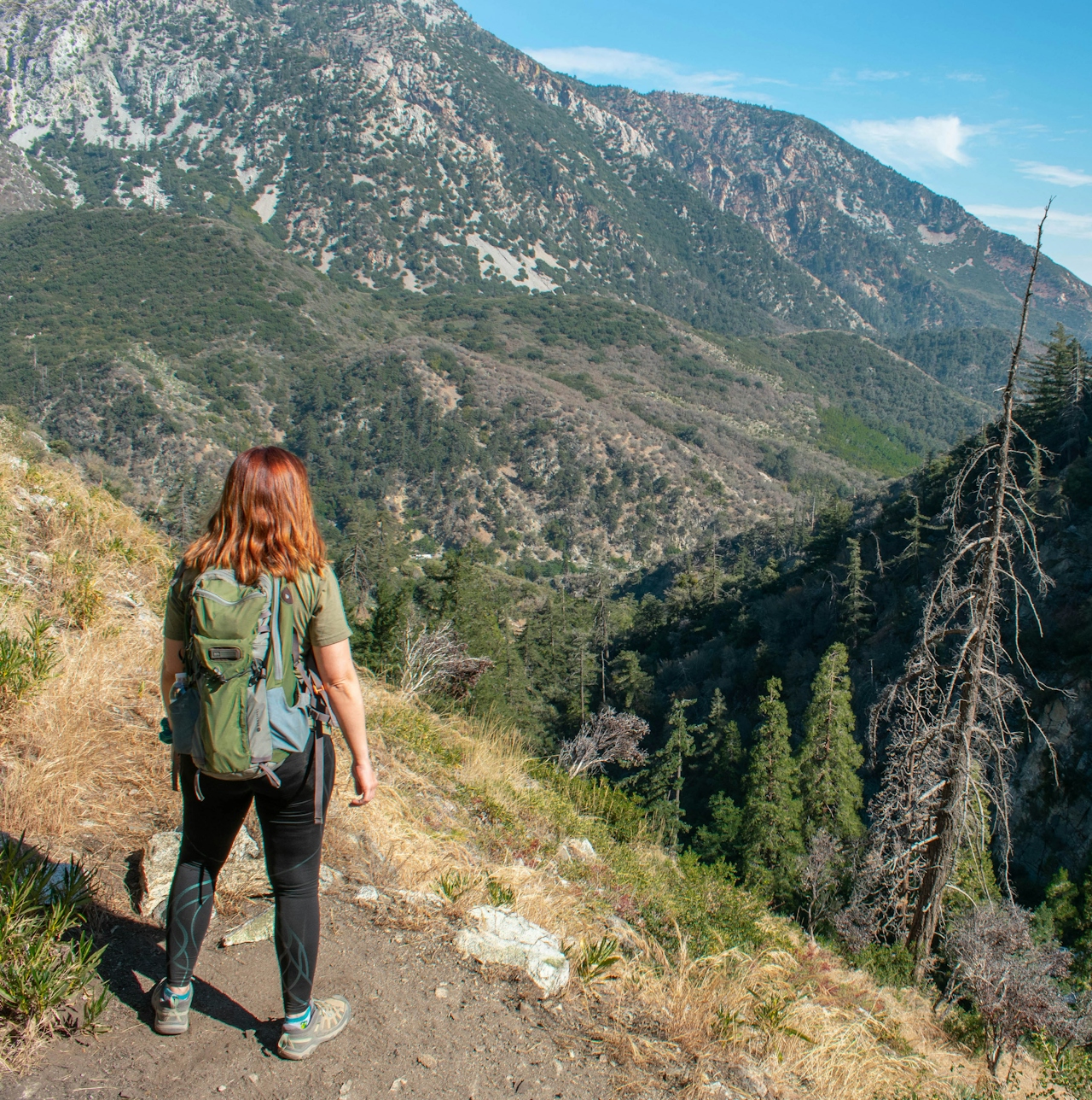 Woman stopped on a trail to look at the big mountain views from the Bear Canyon Trail in Angeles National Forest 