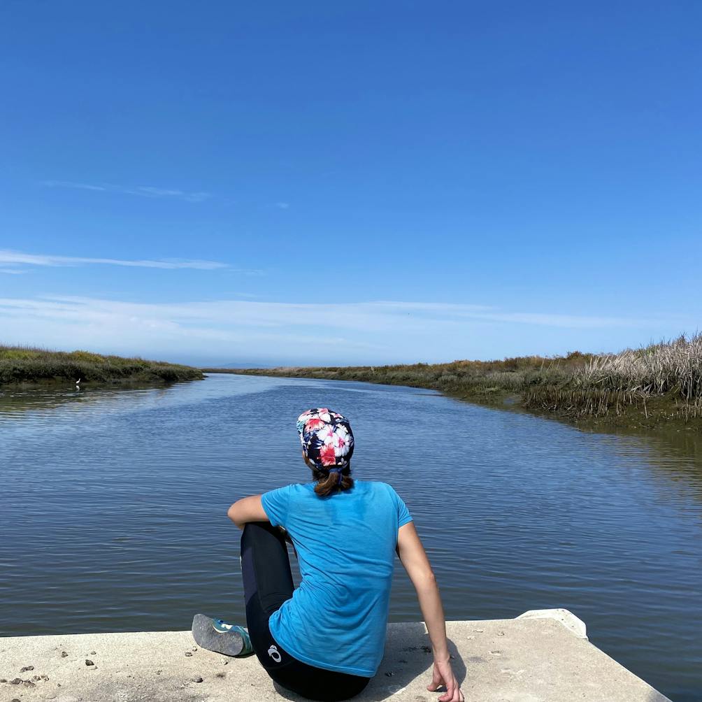 Woman sitting on a dock overlooking the water and marshland in San Jose along the Guadalupe River Trail 