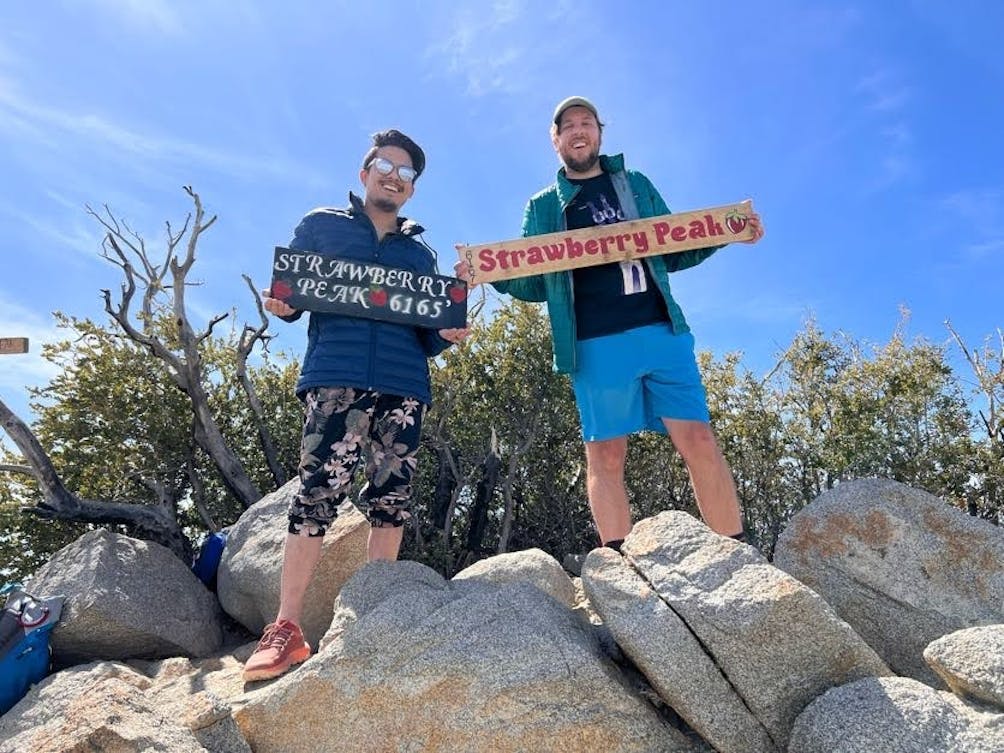 Two hikers holding signs for Strawberry Peak in the San Gabriel Mountains 
