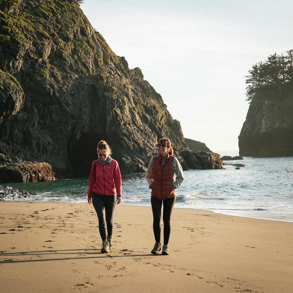 Two friends walking together on the sand at Secret Beach 