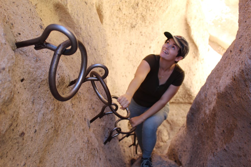 hiker going up a ring cable in Hole in the Wall Rings Loop Trail in the Mojave Desert
