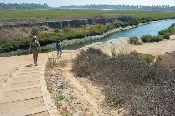 Two hikers go down the stairs towards the waters at Upper Newport Bay Nature Preserve in Orange County 