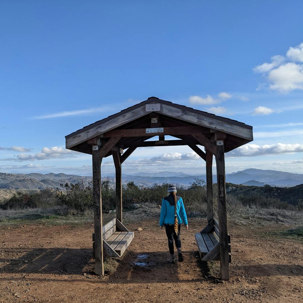 Hiker at bench site overlooking mountains at Escondido Ranch in North San Diego County 