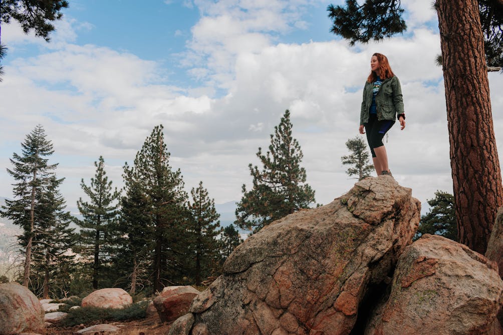 Hiker standing on a boulder surrounded by pine trees at Grays Peak in Big Bear 