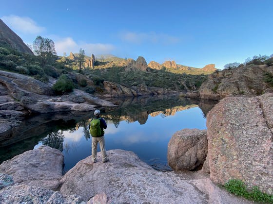 Man standing at small lake overlooking cool rock formations at Pinnacles National Park