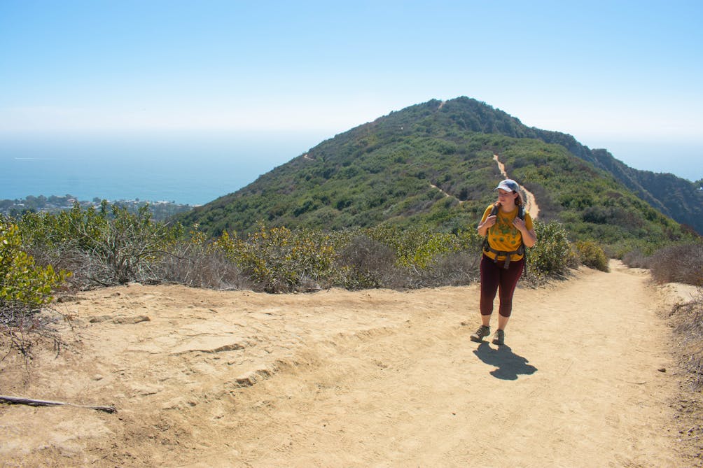 Hiker going up the trail overlooking the ocean at Aliso & Wood Canyons Wilderness Park in Orange County 