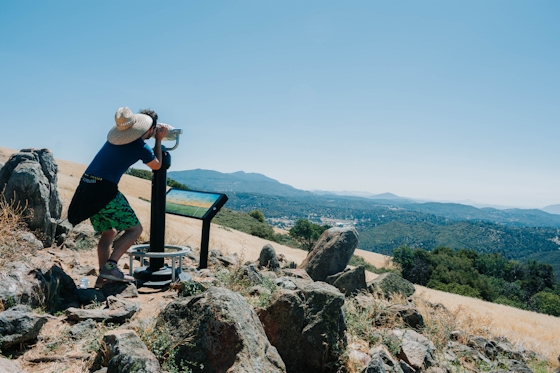 Person peering through telescope at peak of Volcan Mountain in San Diego County near Julian