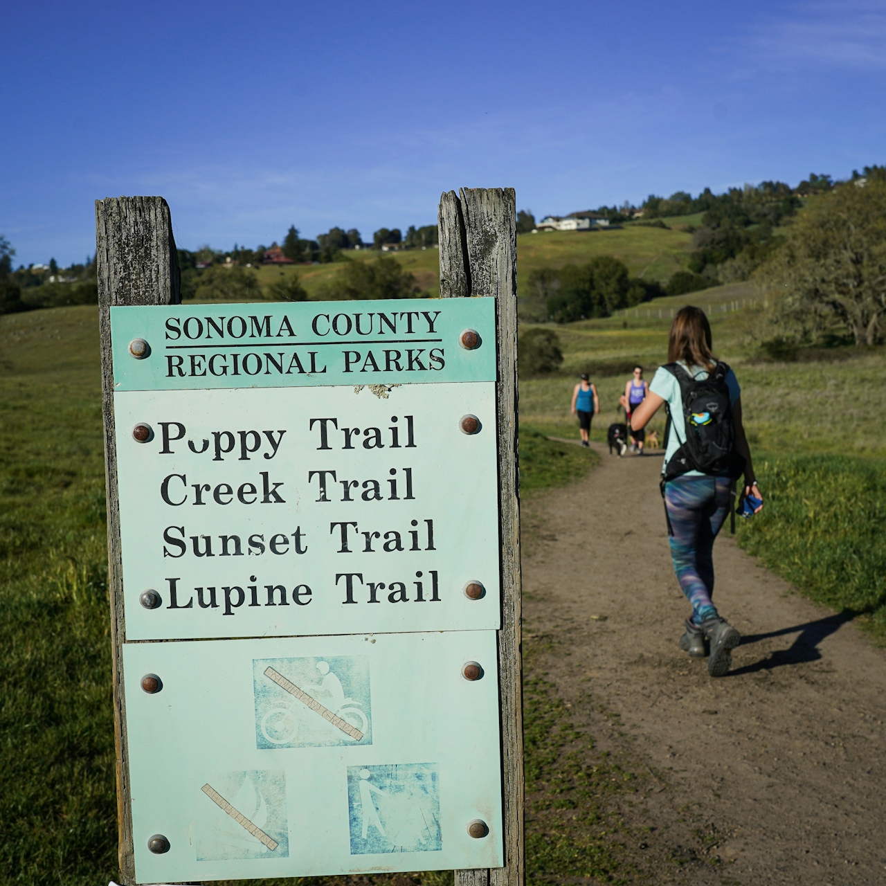 Hiker passing signs for trails at Crane Creek Regional Park in Sonoma County 