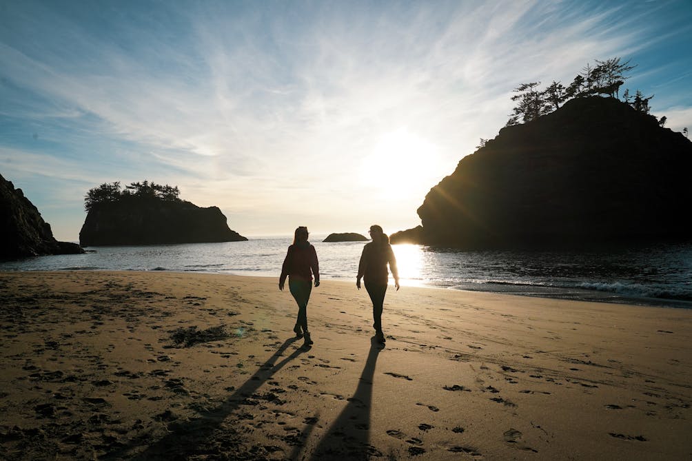 Two friends walking on Secret Beach at sunset on the Oregon Coast