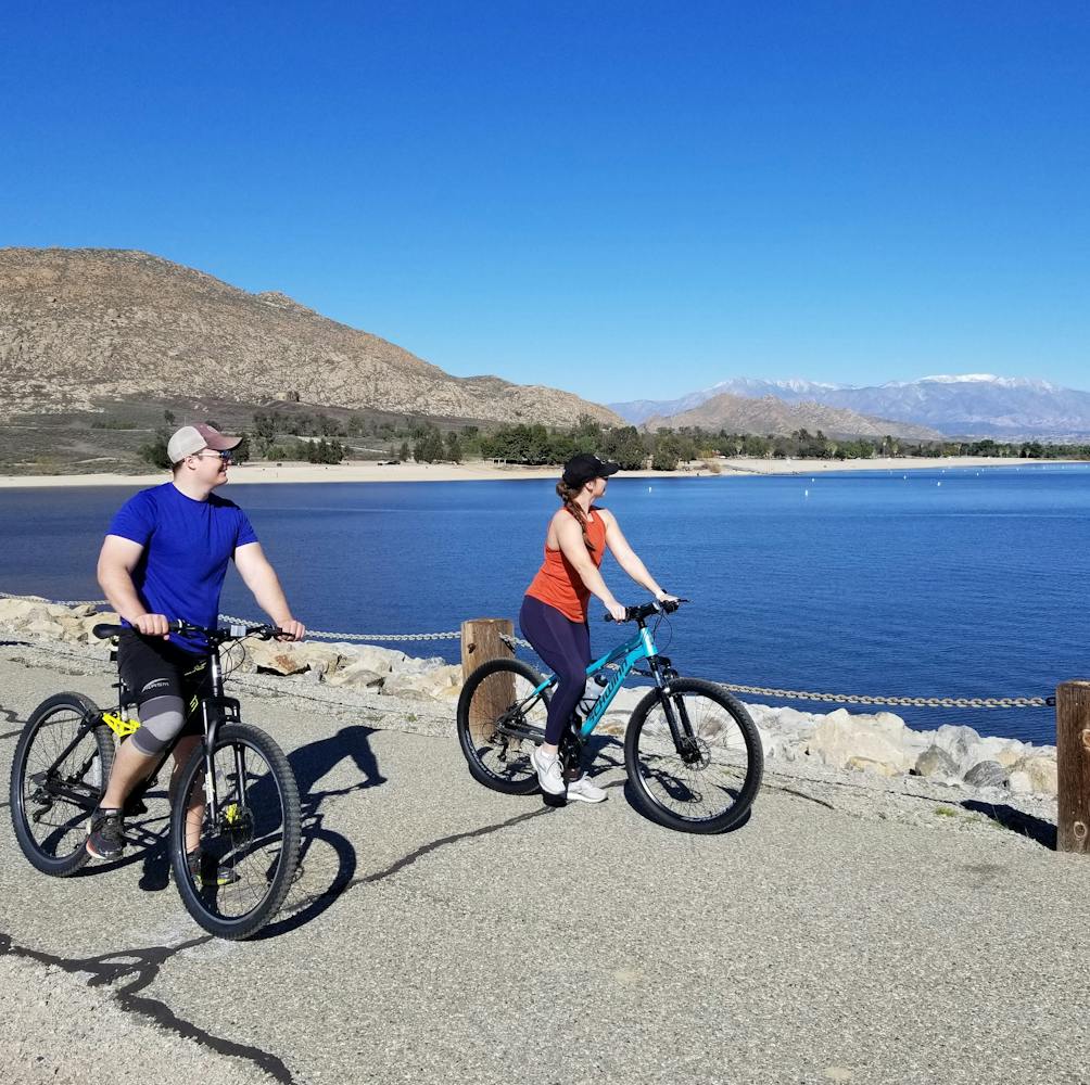 Two people on bikes stopping to look at the lake scenery at Lake Perris in Riverside