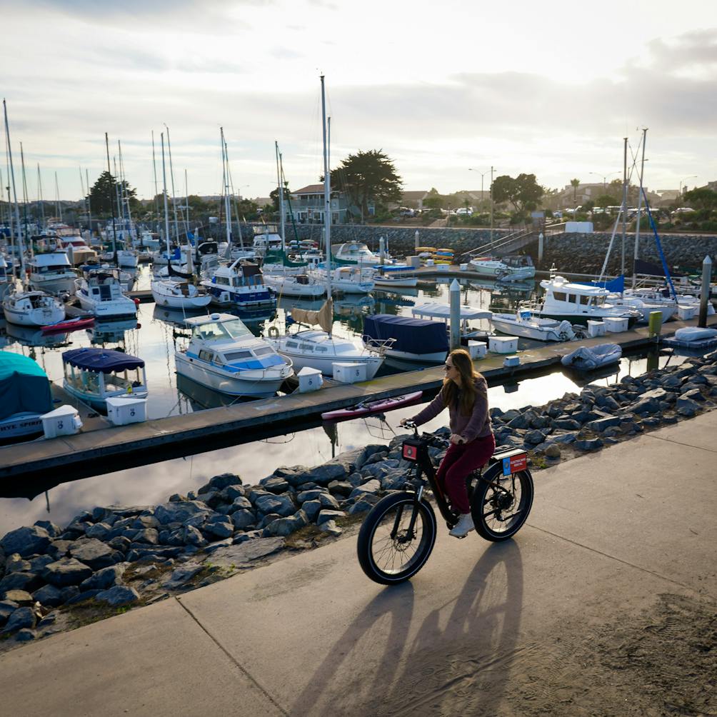Woman on an e-bike at Channel Islands Harbor in Oxnard passing by docked sailboats 