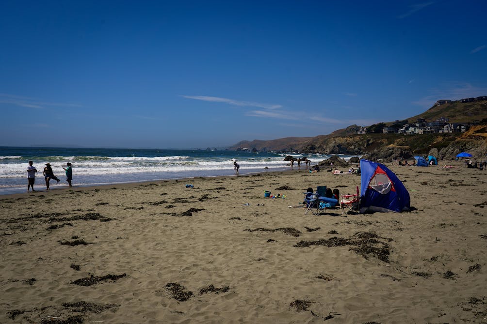 Beach goers hang out on the beach and play in the surf at Dillon Beach in Marin 