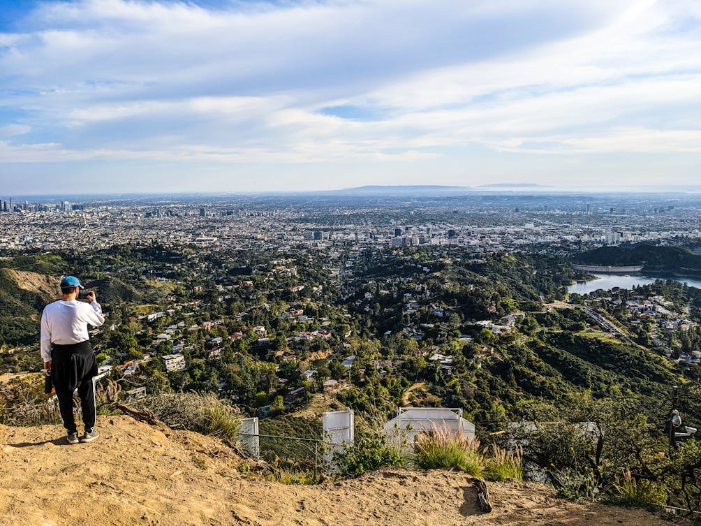 Hiker taking a photo of the Los Angeles city scenery from behind the famous Hollywood Sign in Los Angeles