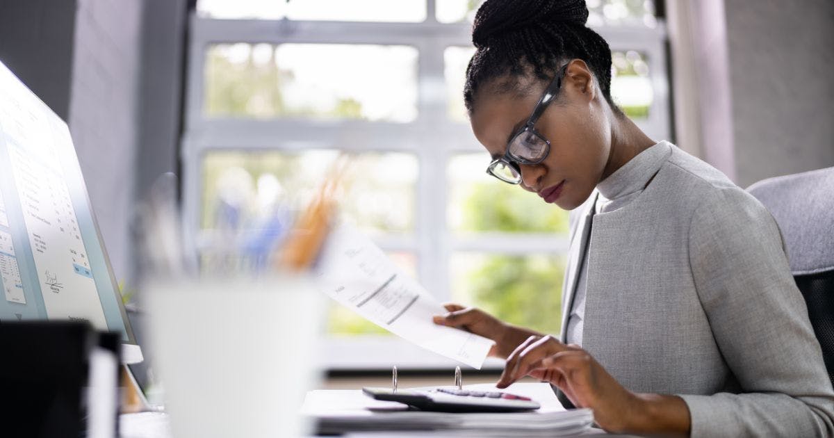 Woman reviewing invoices and calculator during accounts payable process and procedures.