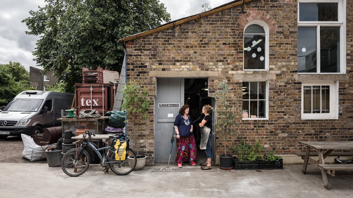 Photograph of two women taking outside a brick printmaking studio.