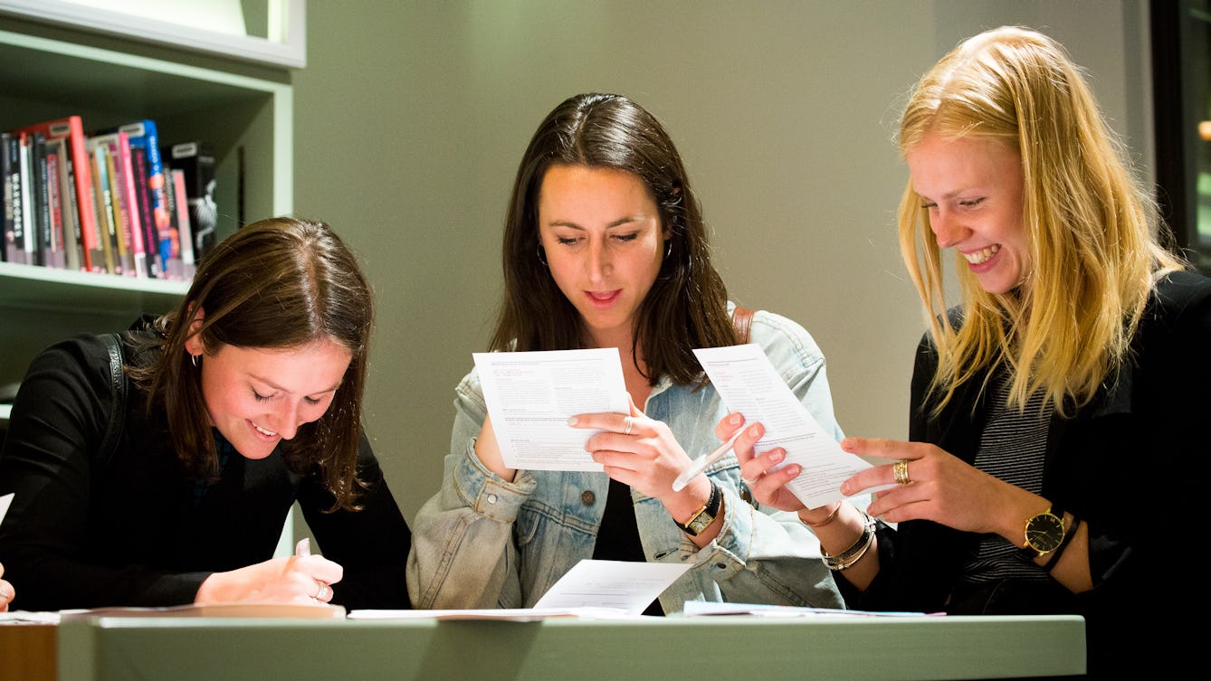 Image of three women looking at paper and writing