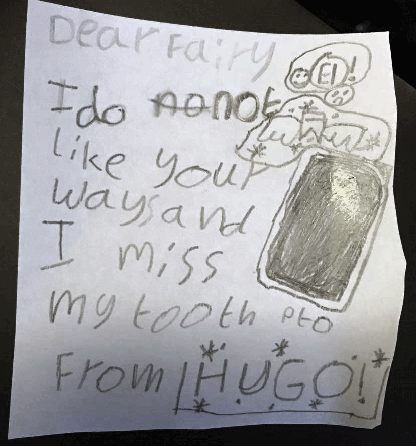 Pencil note on white scrap of paper. Reads: Dear Fairy, I do not like your ways and I miss my tooth. From Hugo. PTO.