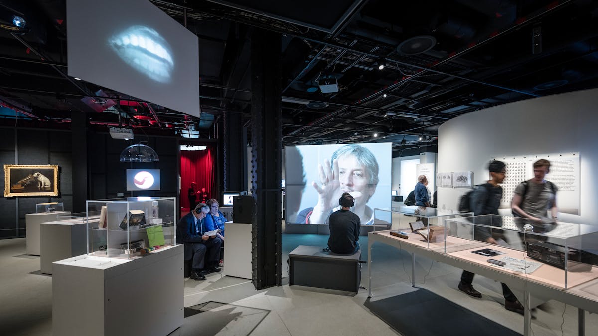 Photograph of visitors exploring the exhibition, This is a Voice at Wellcome Collection.