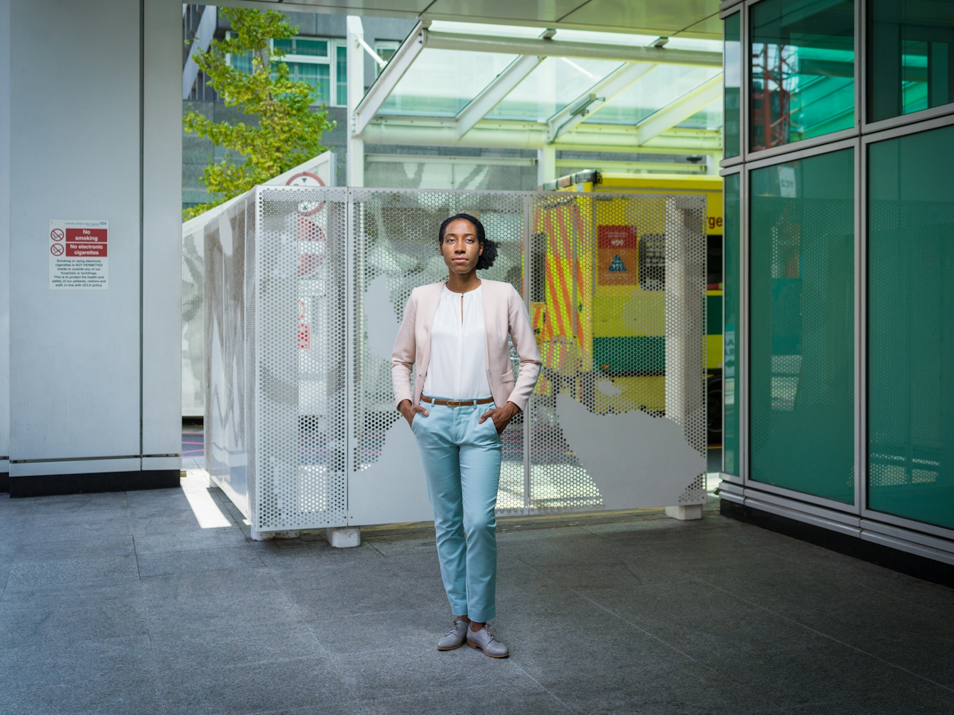Photographic full length portrait of Sarah Itam, urological surgeon, outside University College London Hospital.