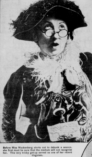 Black and white photo of a woman with a surprised expression wearing a hat and fancy scarf.