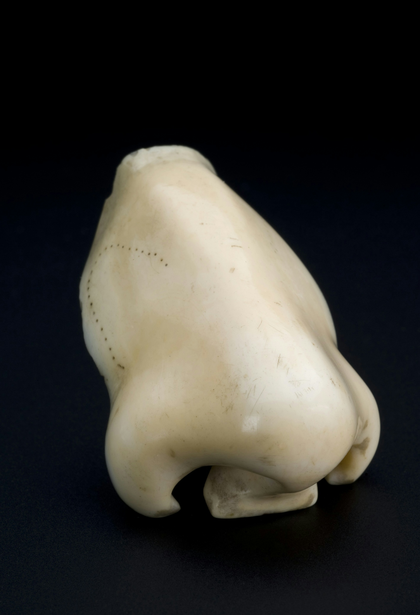 A piece of porcelain in the shape of a human nose on a dark background.