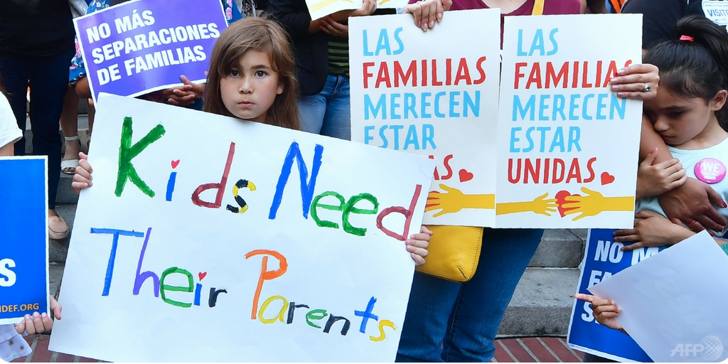 Children demonstrate with signs reading 'Kids need their parents'.
