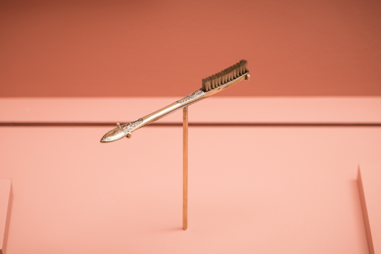 Photograph of Napoleon's toothbrush displayed on a thin post within an exhibition display case as part of the Teeth exhibition at Wellcome Collection.