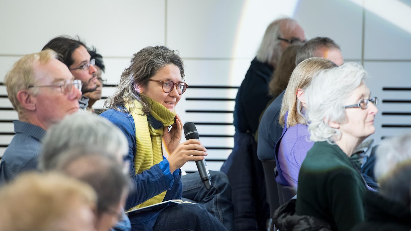 Photograph of the audience in the Forum at Wellcome Collection. A female audience member has a microphone in her hand