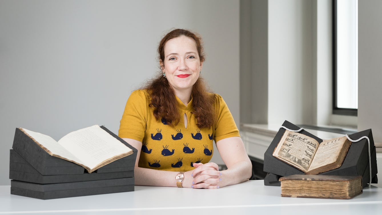 Photograph of Dr  Kathleen Walker-Meikle sitting at a table in front of manuscripts from Wellcome Collection. 