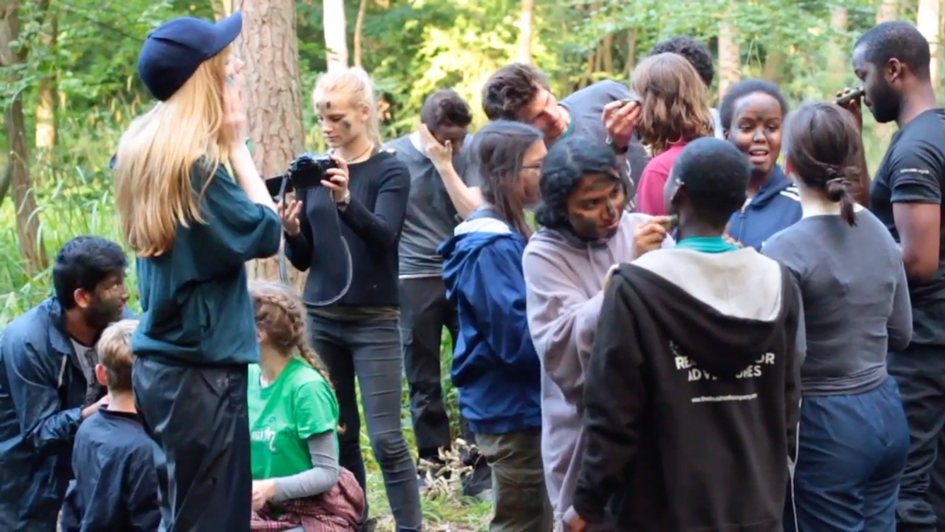 Film still showing young people painting their faces in a forest, part of 'Disconnected' a RawMinds film project.