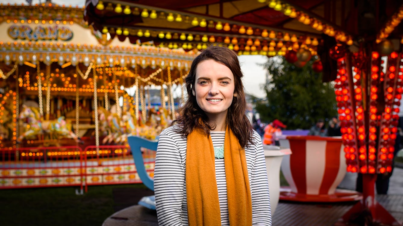 Photographic portrait of Emma Purce at a colourfully lit fairground.