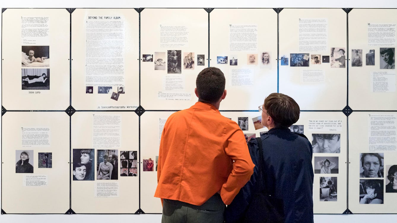 Photograph of two people in the Misbehaving Bodies Exhibition. They have their backs to the camera looking at a display on the wall.