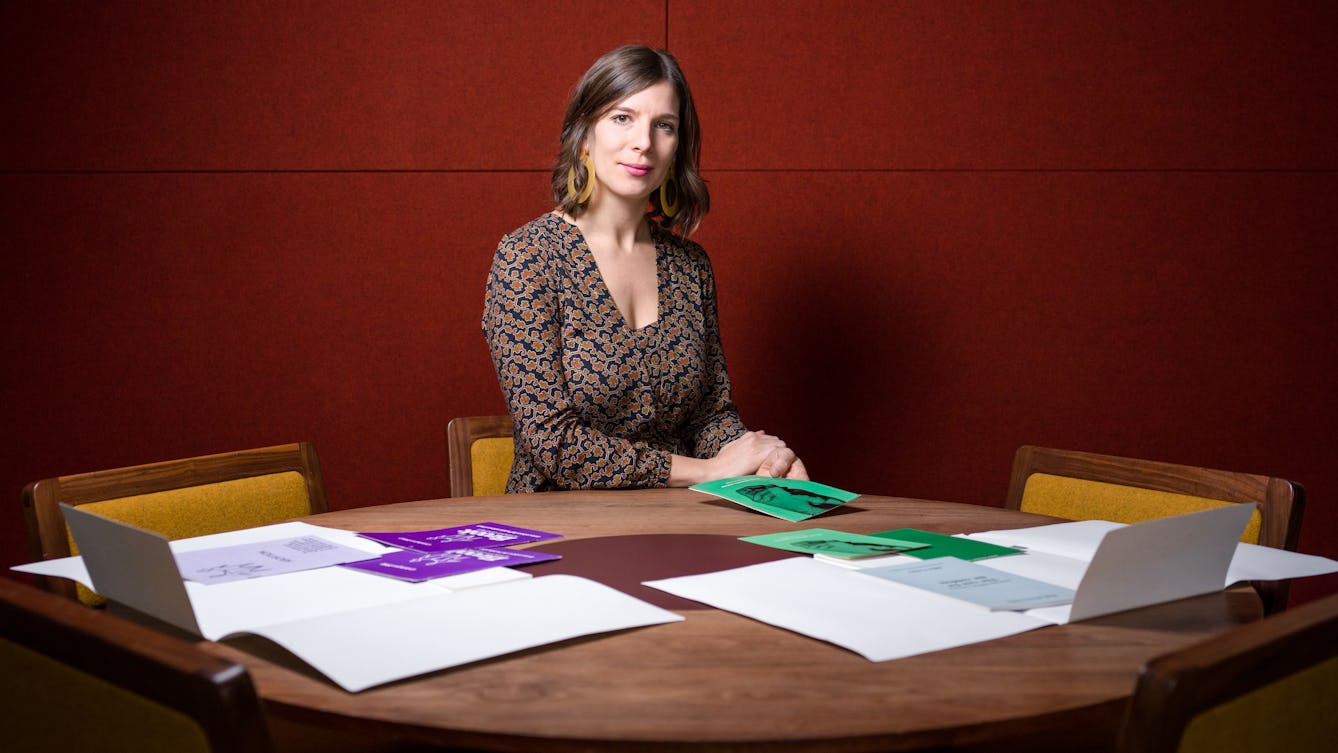 Photograph of Dr Caroline Rusterholz sitting at a table in front of a selection of Wellcome Collection library archive material.