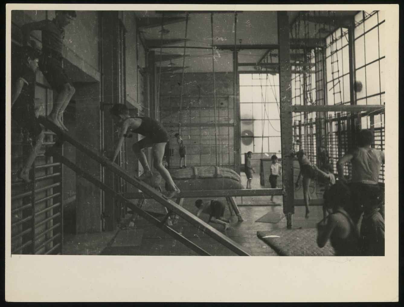 Black and white photograph showing boys and young men exercising in a gymnasium.