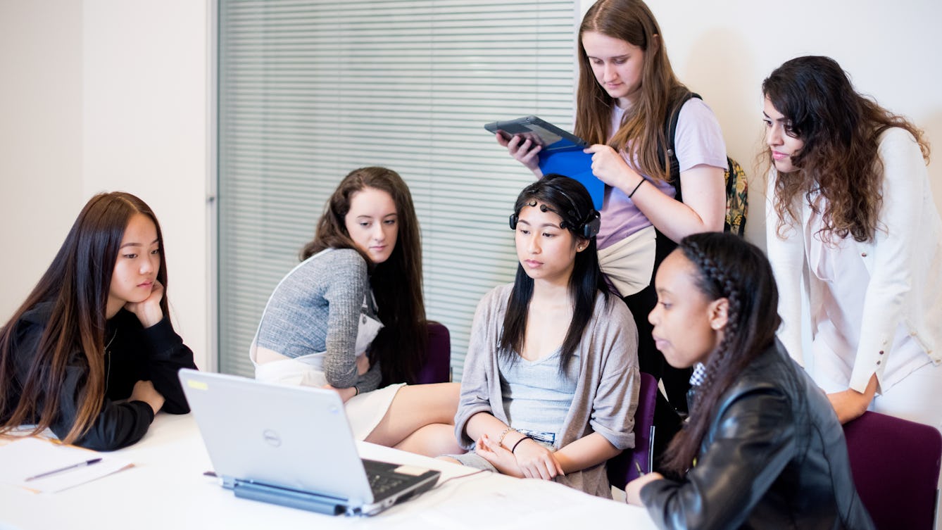 Photograph of a group of young people gathered around a laptop computer, engaged in a workshop at Wellcome Collection.