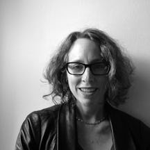 Portrait photograph of a woman with glasses and collar-length hair, smiling.