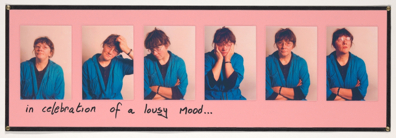 Photograph of a pink sheet of paper with 6 colour photographs mounted on top in a row. Each images shows a woman in a blue dressing gown pulling a different pose. Sometimes arms folded, one with her head in hands, another scratching her head. Under the row of photographs are the handwritten words, "in celebration of a lousy day". The whole collage is laminated.