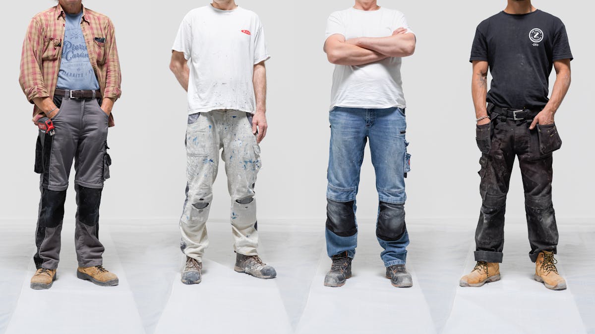 Photograph of four male builders from the neck down against a grey background. Each man is wearing a different outfit depending upon his trade.