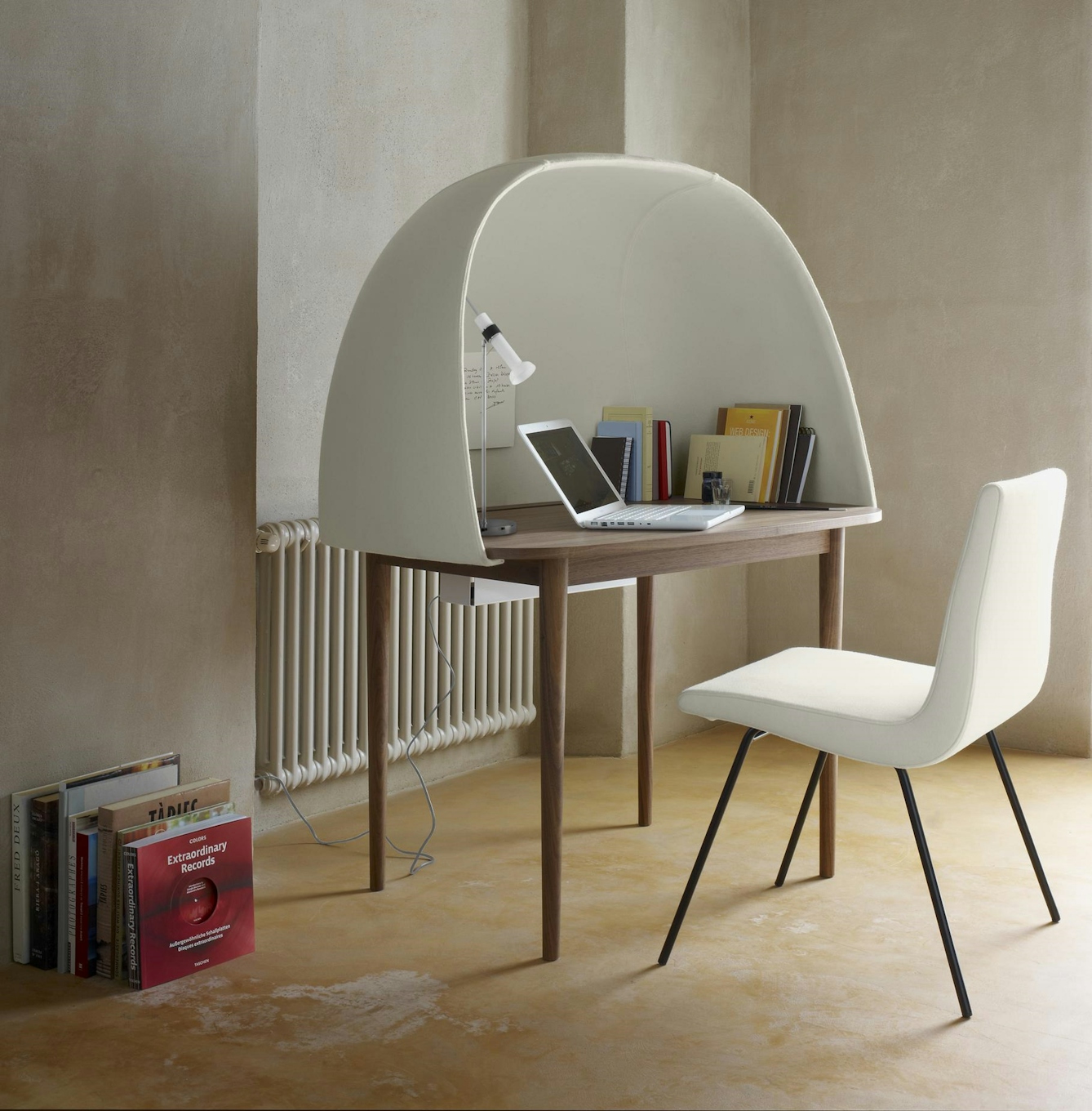 Colour photograph of a walnut wood desk with a white curved shield surrounding it on three sides.