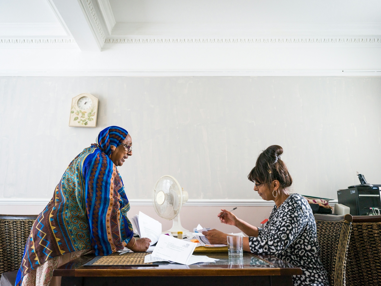 Photograph of Sarifa Patel with her personal assistant working at a table in her living room.