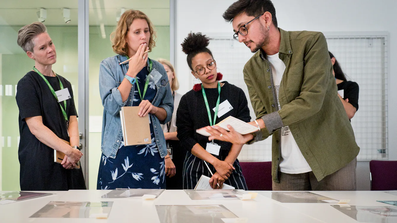Photograph showing visitors examining archive material displayed on a table.