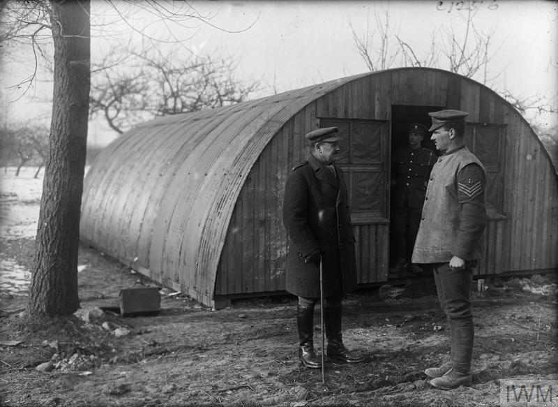 Photo of a curved metal hut with soldiers standing out the front.