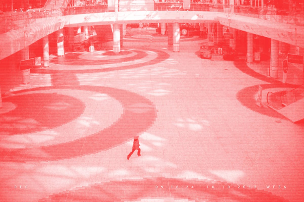Pixellated photograph from a shopping mall security camera, where all adults have been crudely 'Photoshopped' out of the image, leaving one remaining child. The image has a red/pink tone applied to it.